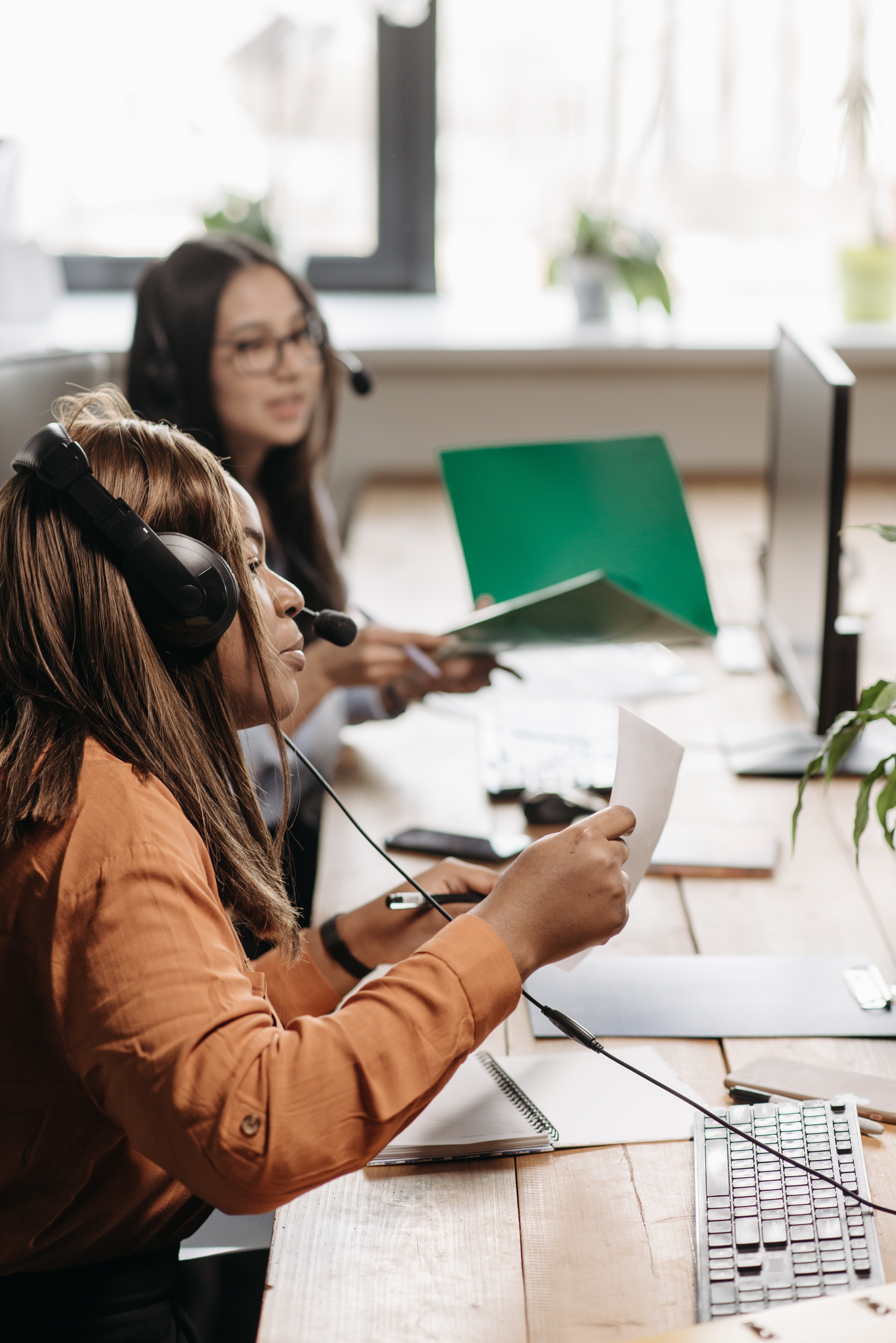 Vrouw achter het bureau aan het bellen met een headset op